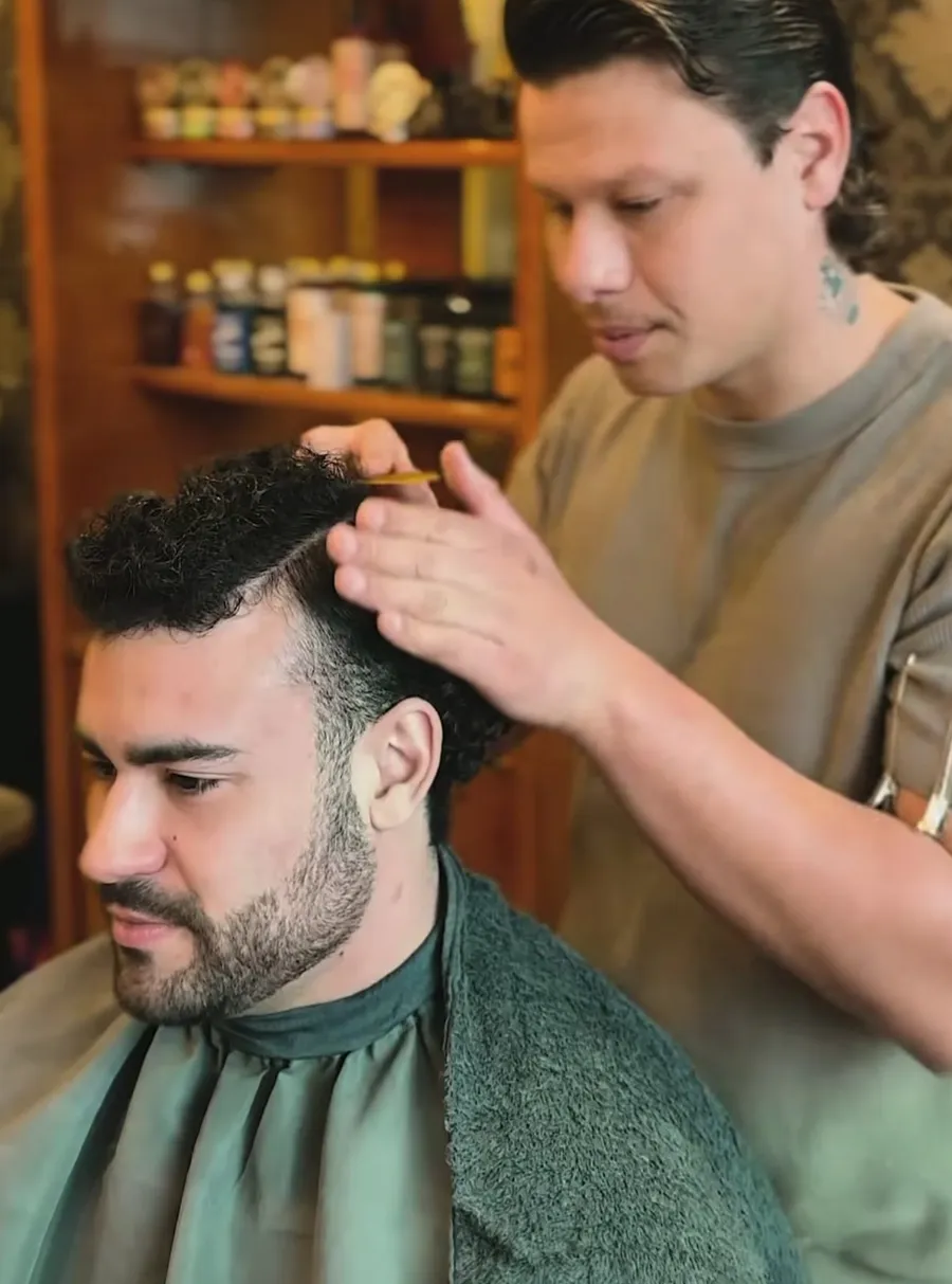 Barbeiro ajeitando o cabelo cacheado de um cliente