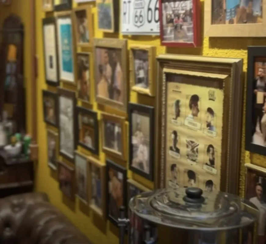 Cantinho do café com garrafa térmica, sofá de couro e quadros na parede